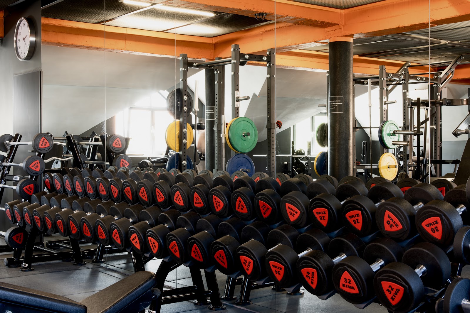 Strefa wolnych ciężarów Trim Fitness z pomarańczową konstrukcją